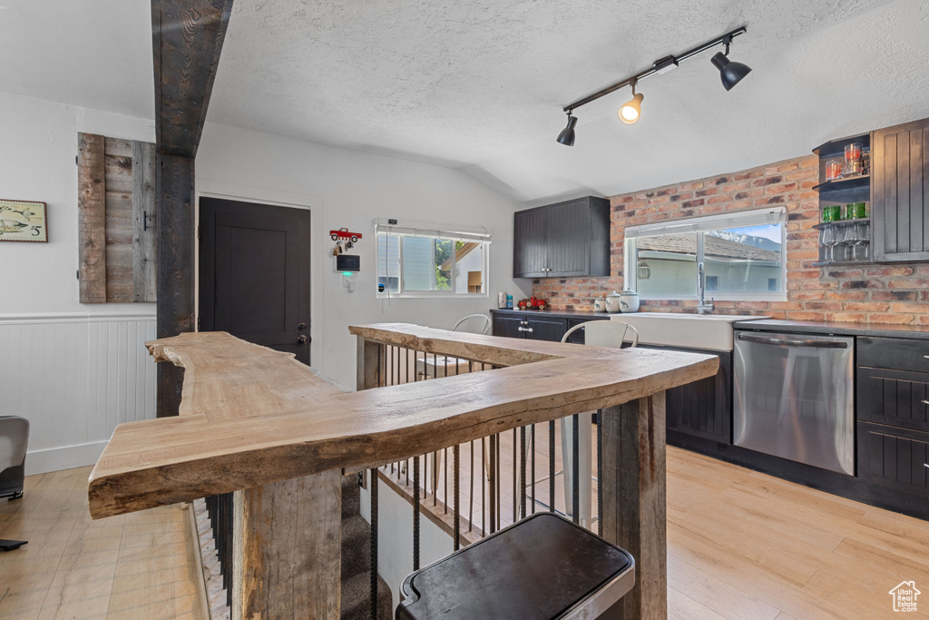 Kitchen with dishwasher, wainscoting, light wood-style flooring, a textured ceiling, and a sink