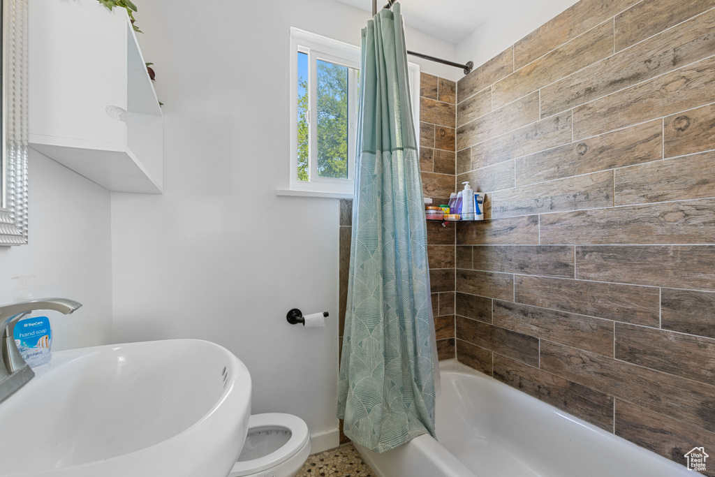 Bathroom featuring shower / tub combo with curtain, a sink, baseboards, and toilet