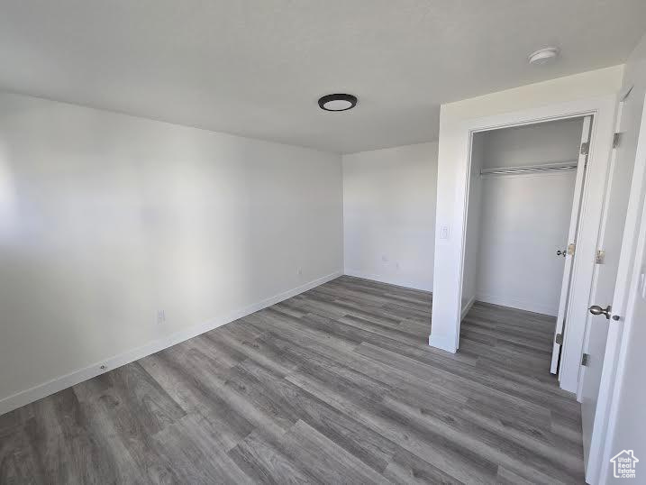 Unfurnished bedroom featuring wood finished floors, a closet, and baseboards