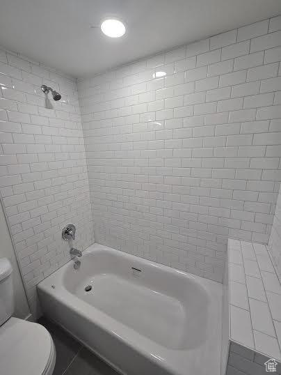 Full bathroom featuring toilet, tile patterned floors, and shower / washtub combination