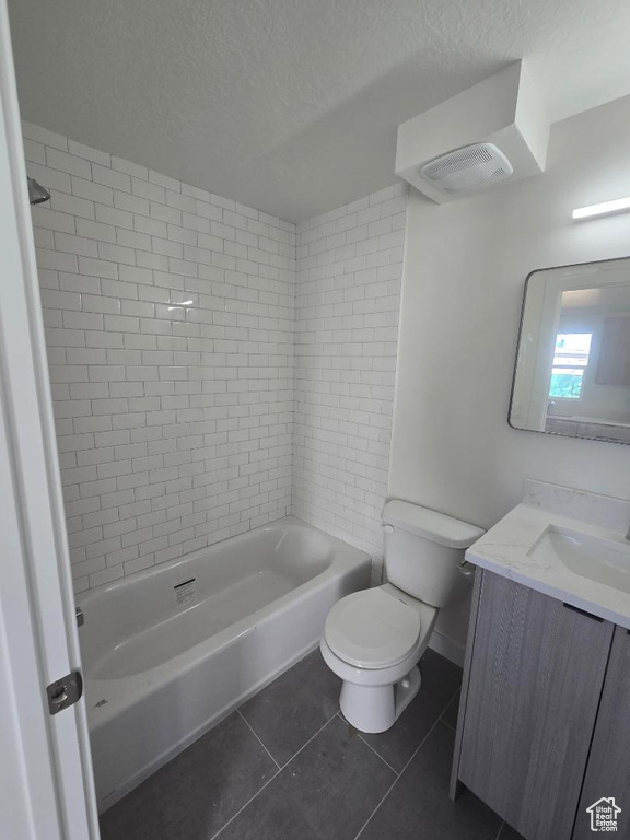 Full bath with toilet, a textured ceiling, tile patterned flooring, vanity, and washtub / shower combination