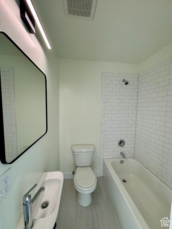 Bathroom with toilet, tile patterned flooring, shower / tub combination, and baseboards