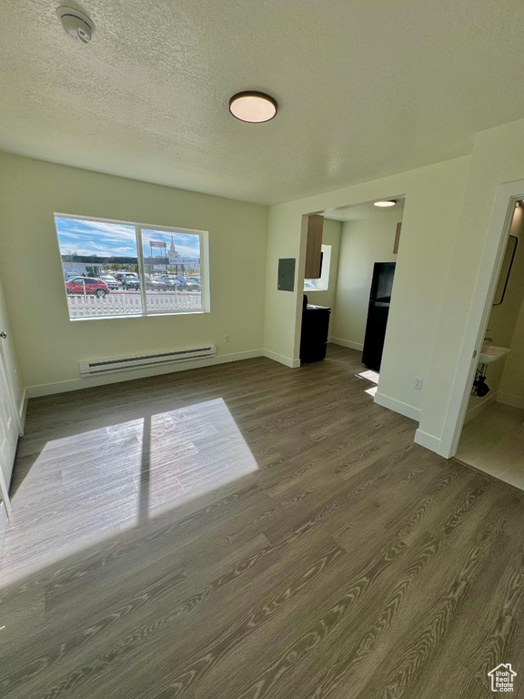 Unfurnished living room featuring a baseboard radiator, dark wood-style flooring, baseboards, and a textured ceiling
