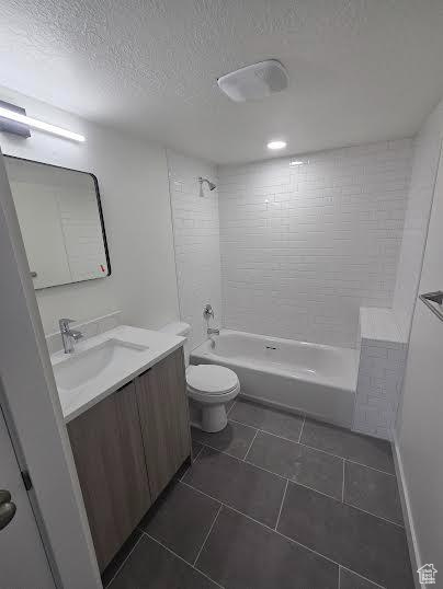 Full bath with vanity, toilet, tile patterned flooring, a textured ceiling, and shower / washtub combination