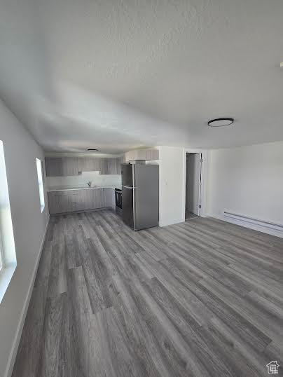 Unfurnished living room featuring dark wood-style floors and baseboards