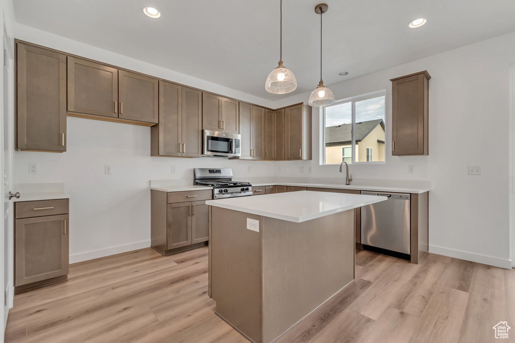Kitchen featuring appliances with stainless steel finishes, light wood-style flooring, a kitchen island, light countertops, and recessed lighting