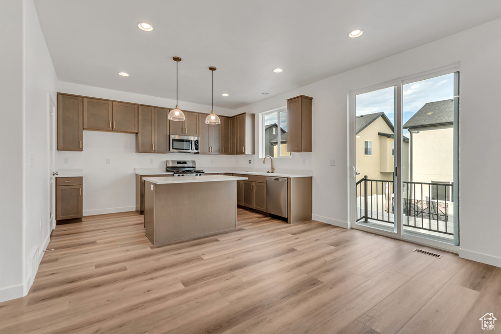Kitchen featuring stainless steel appliances, light wood-style floors, light countertops, a kitchen island, and recessed lighting