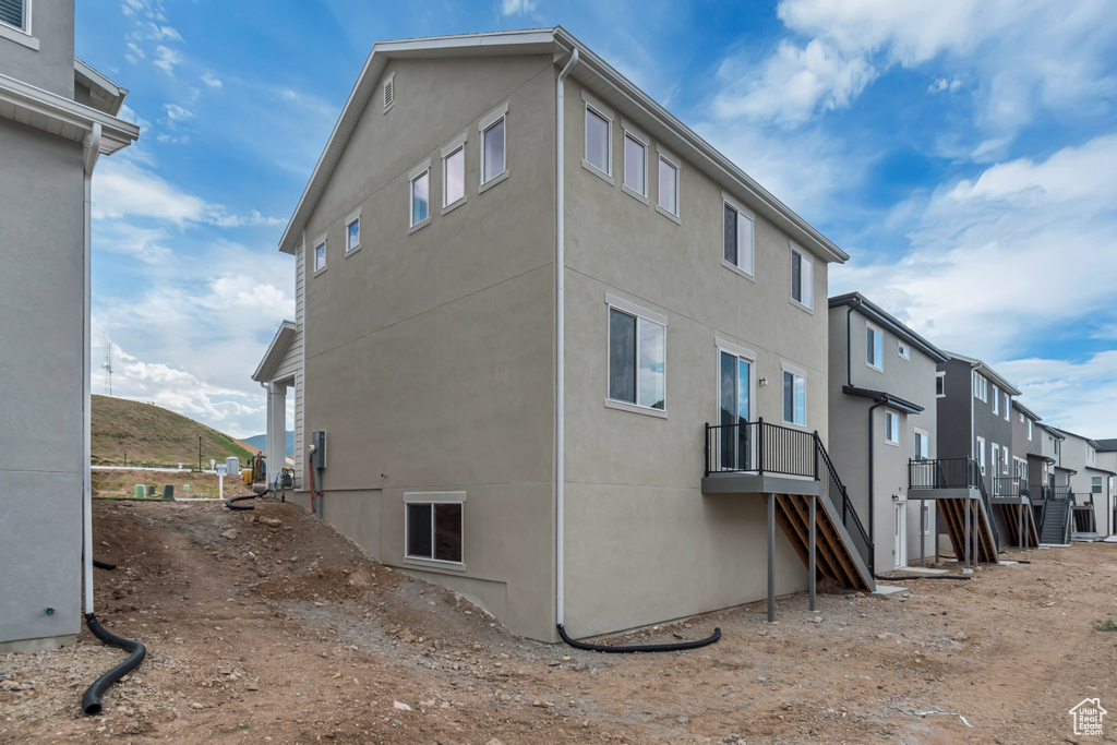 View of side of property with stucco siding, stairway, and a residential view