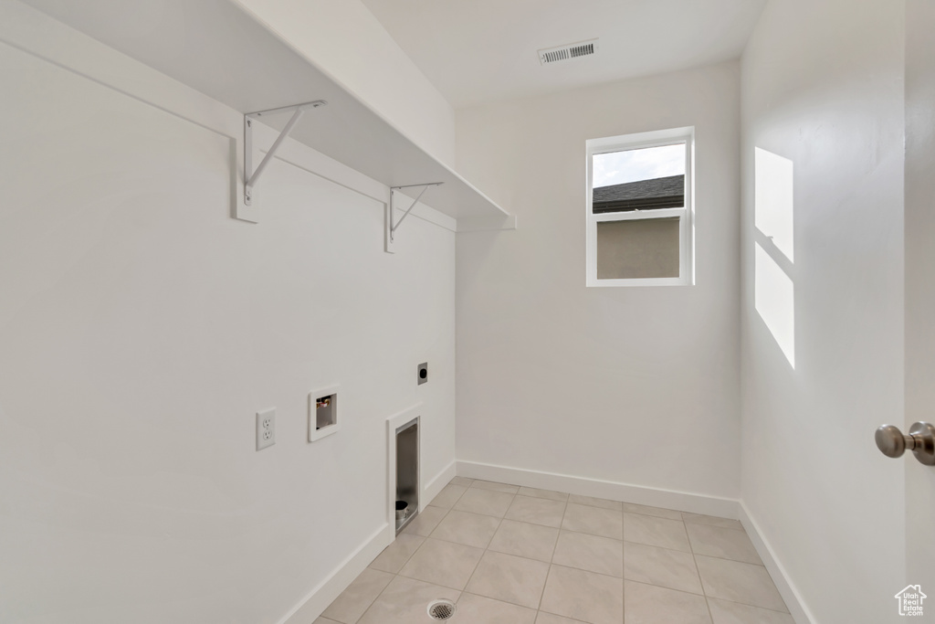 Washroom featuring hookup for an electric dryer, hookup for a washing machine, and light tile patterned floors