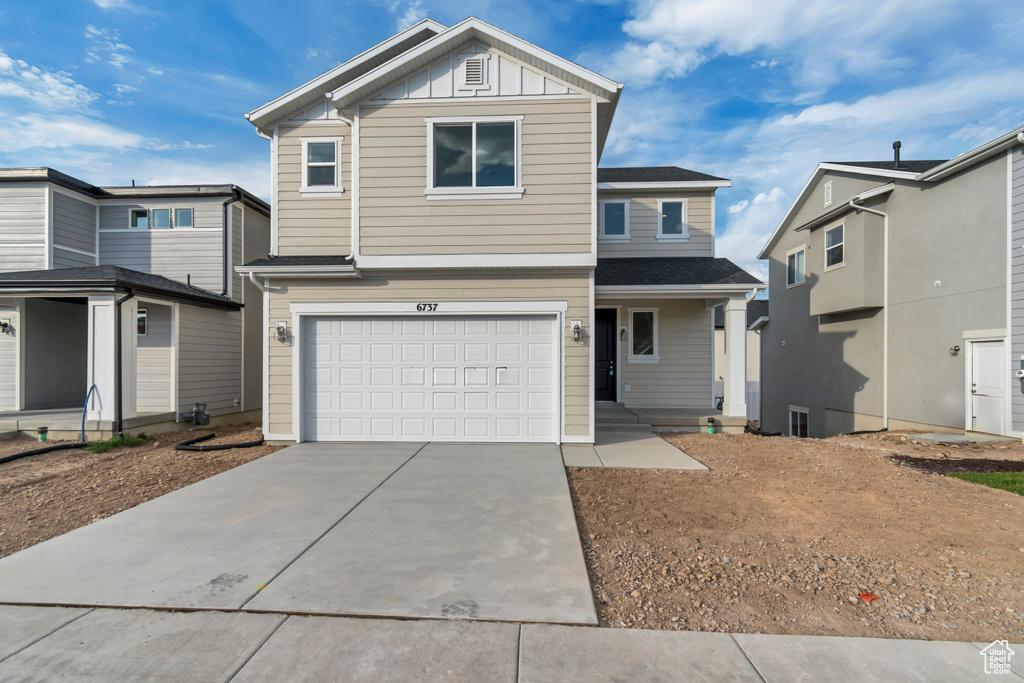 View of front of home with an attached garage, driveway, and board and batten siding