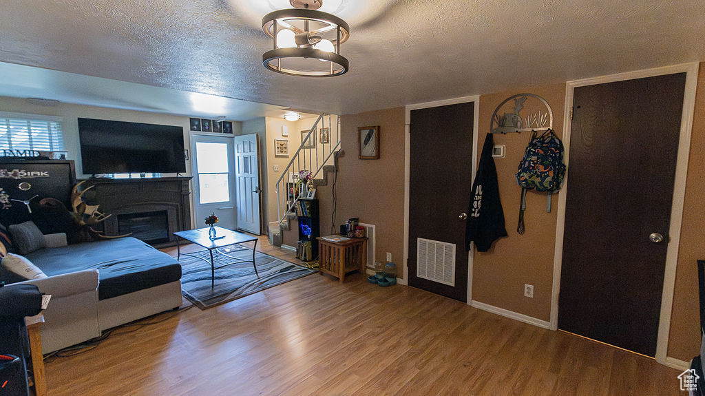 Living room with wood finished floors, stairs, baseboards, a textured ceiling, and a fireplace