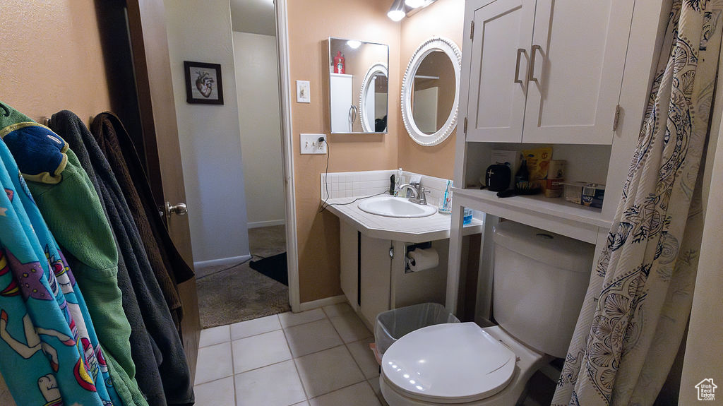 Full bathroom with toilet, vanity, tile patterned flooring, and baseboards