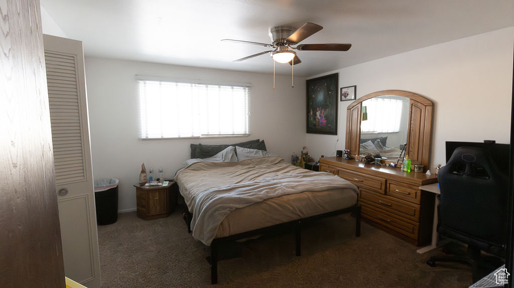 Carpeted bedroom featuring ceiling fan and an office area