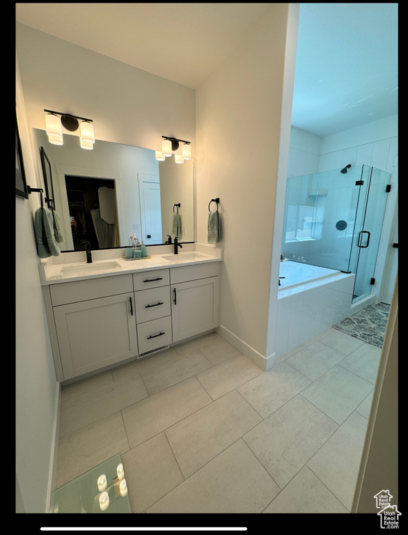 Full bath with double vanity, a bath, a stall shower, baseboards, and tile patterned flooring