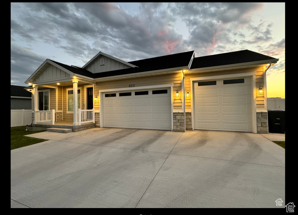 View of front of house with stone siding, board and batten siding, driveway, and a garage