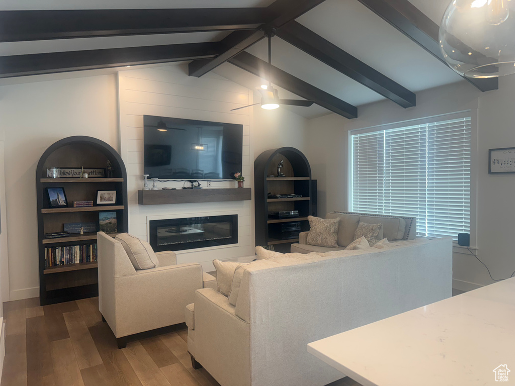 Living room with wood finished floors, a glass covered fireplace, and ceiling fan
