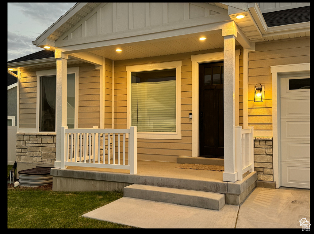Entrance to property featuring stone siding, a porch, and board and batten siding