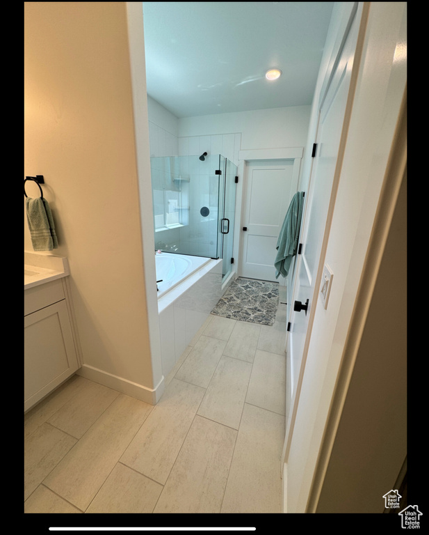 Bathroom with a shower stall, a garden tub, vanity, recessed lighting, and baseboards