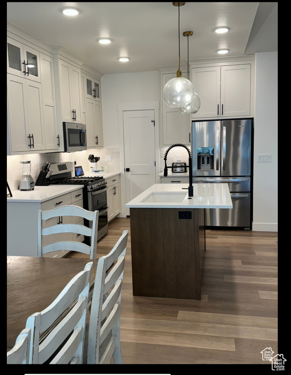 Kitchen with appliances with stainless steel finishes, dark wood-style floors, white cabinets, glass insert cabinets, and recessed lighting