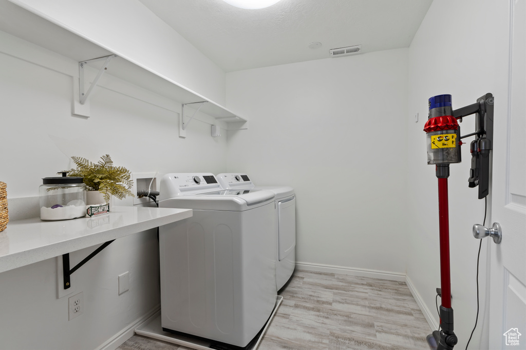 Washroom featuring independent washer and dryer, light wood-style flooring, and baseboards