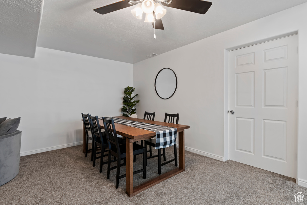 Dining area with carpet flooring, a ceiling fan, and baseboards
