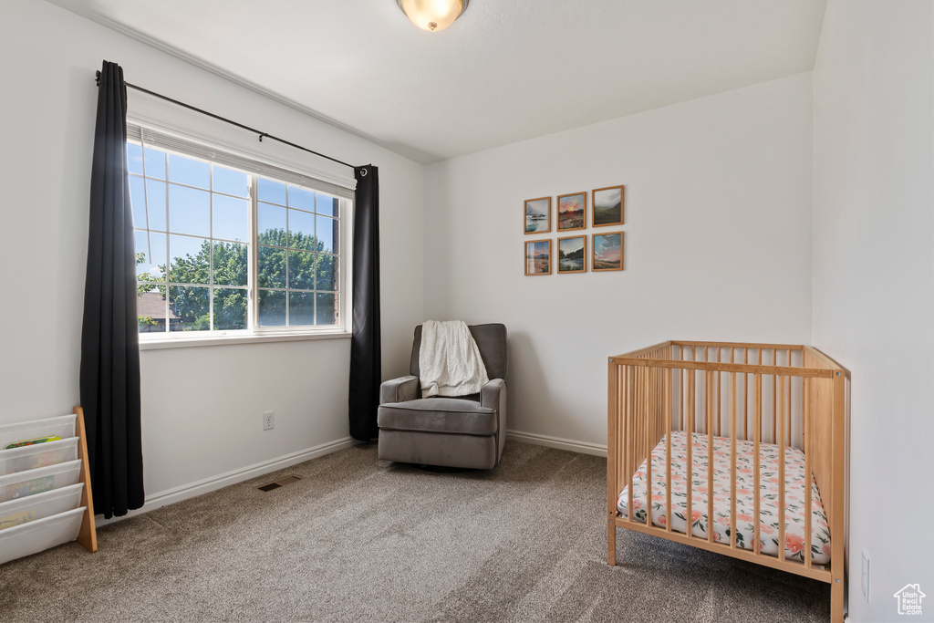Carpeted bedroom featuring a crib and baseboards