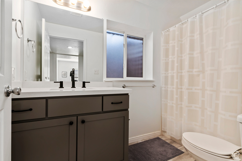 Full bath featuring vanity, toilet, curtained shower, and baseboards