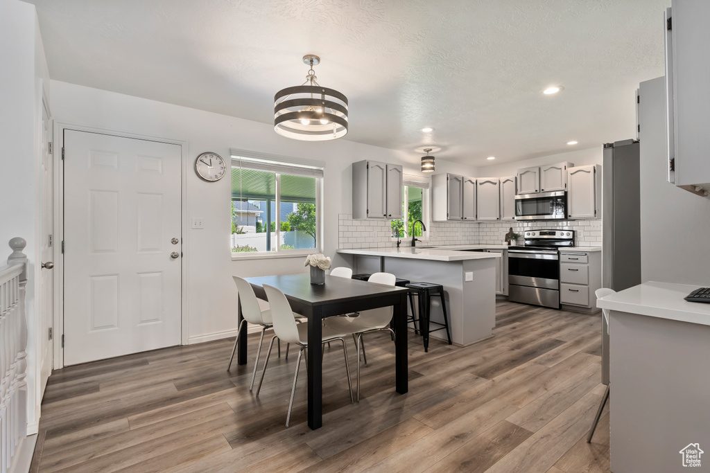 Dining space with wood finished floors, a chandelier, and recessed lighting