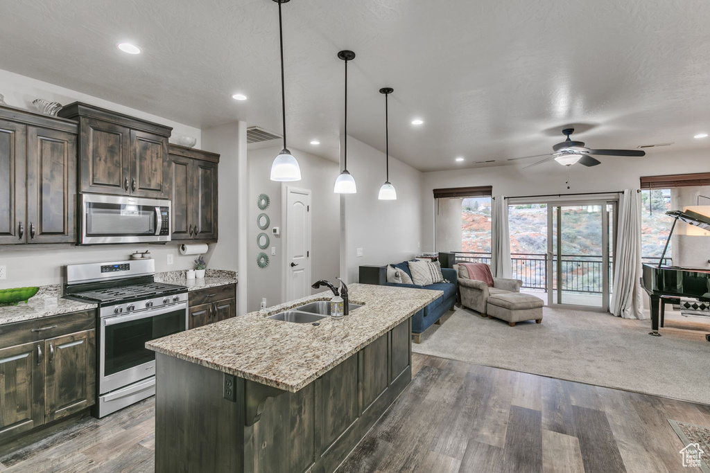 Kitchen with appliances with stainless steel finishes, a sink, ceiling fan, dark brown cabinetry, and open floor plan