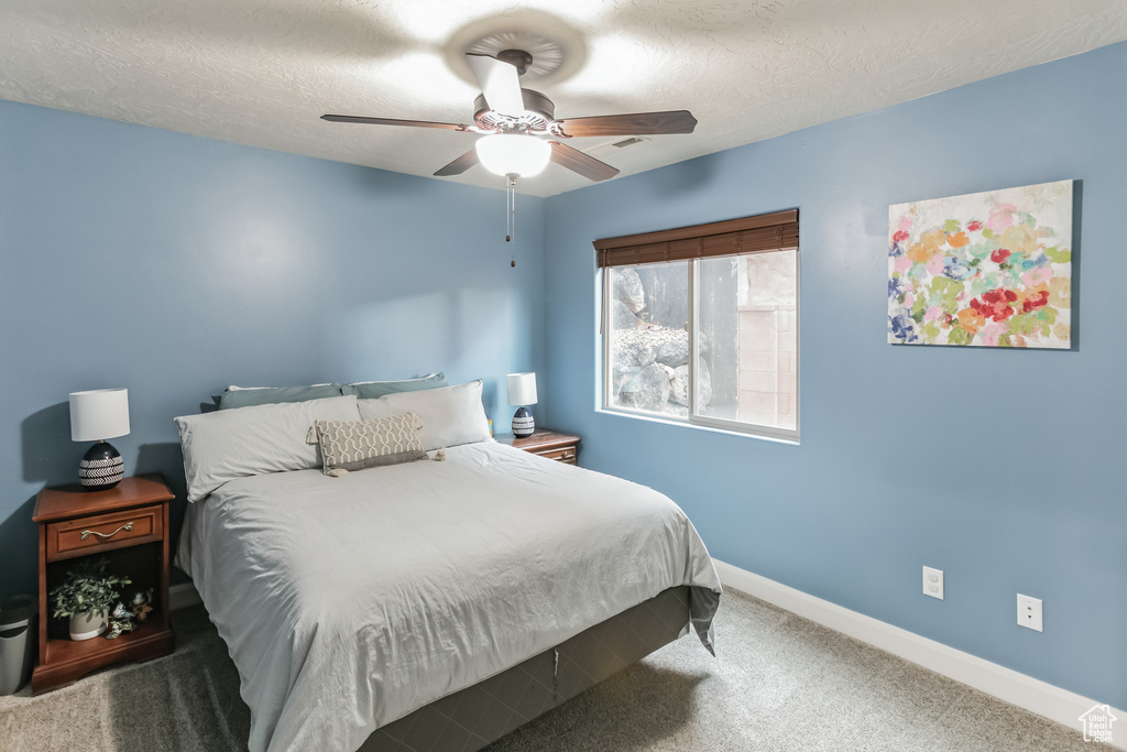 Bedroom with baseboards, carpet floors, ceiling fan, and a textured ceiling