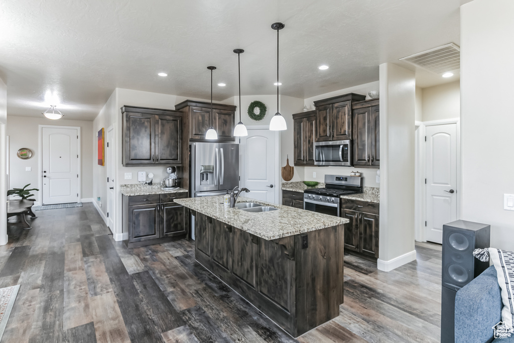 Kitchen with appliances with stainless steel finishes, dark brown cabinetry, baseboards, a sink, and recessed lighting