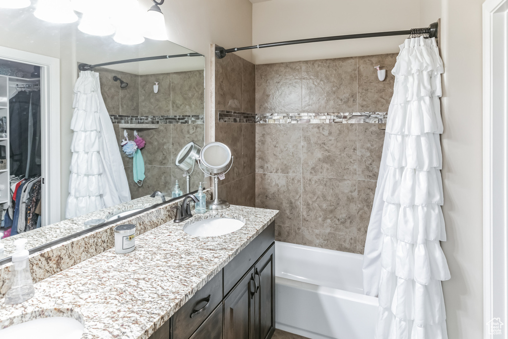 Full bathroom with double vanity, shower / tub combo with curtain, and a spacious closet