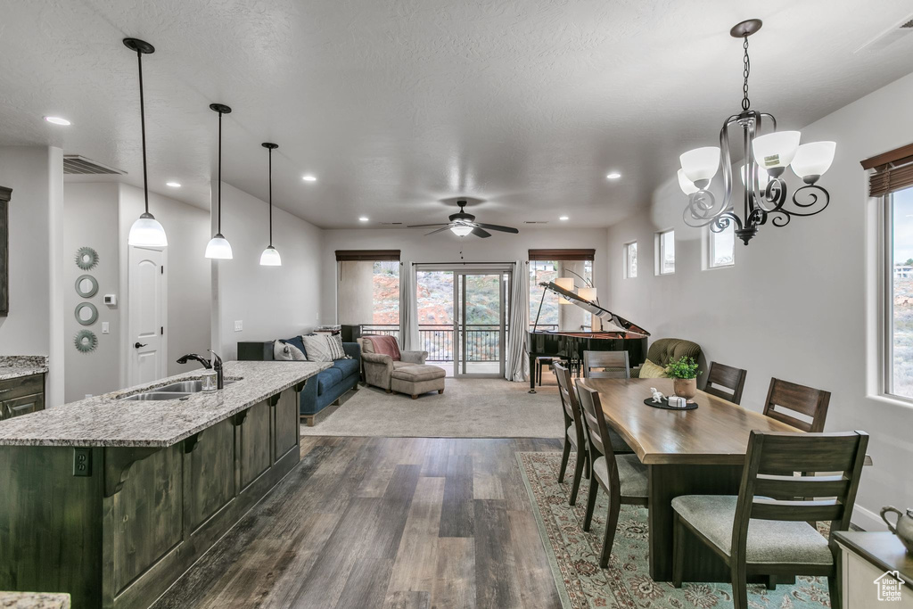Dining room with dark wood-type flooring, ceiling fan, recessed lighting, and a chandelier