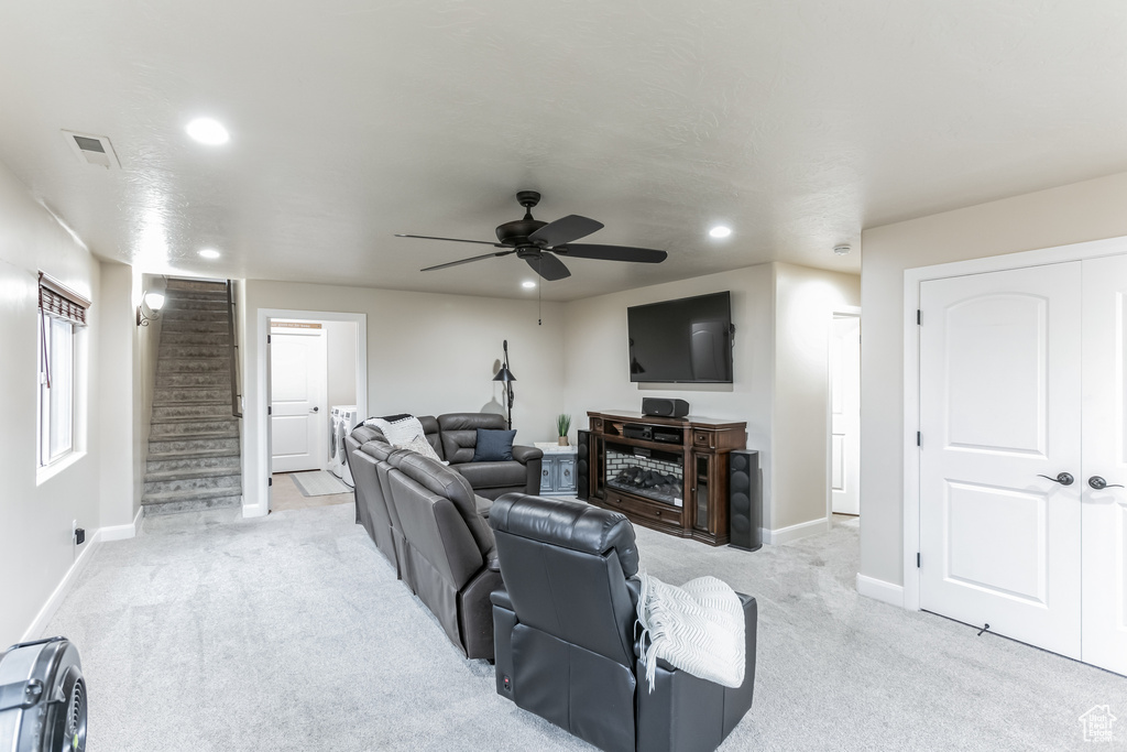 Living area featuring recessed lighting, light carpet, baseboards, a ceiling fan, and stairs