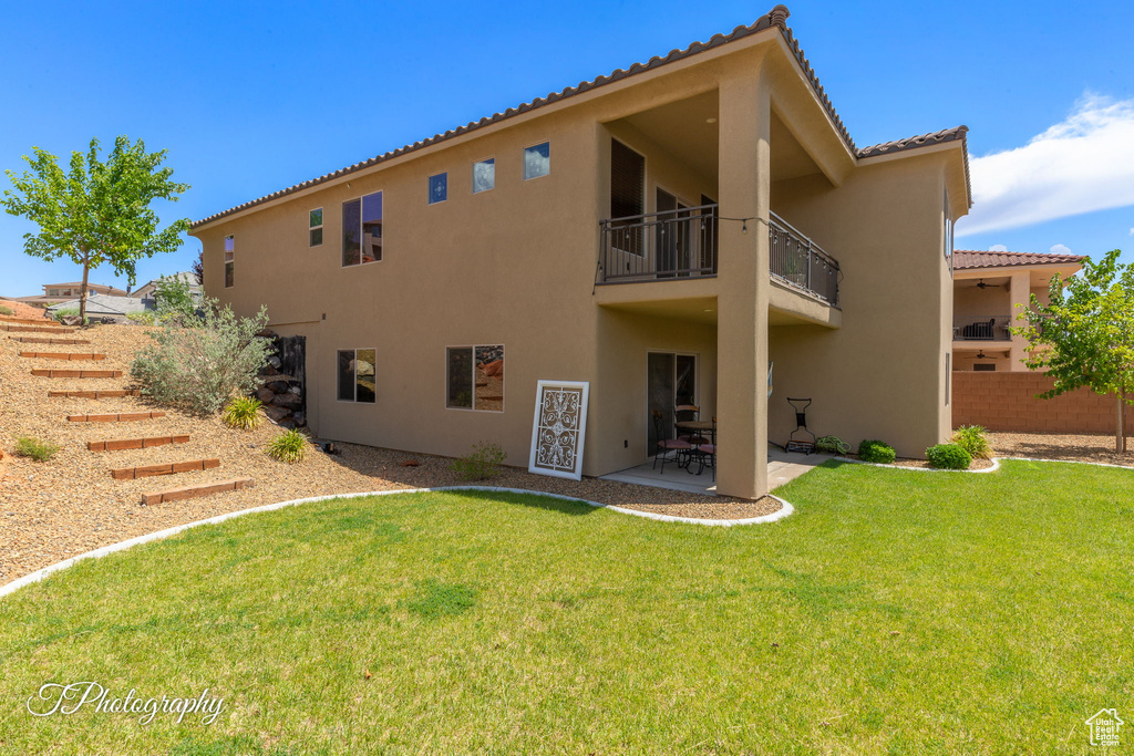 Back of house with a balcony, stucco siding, a patio area, and a tiled roof