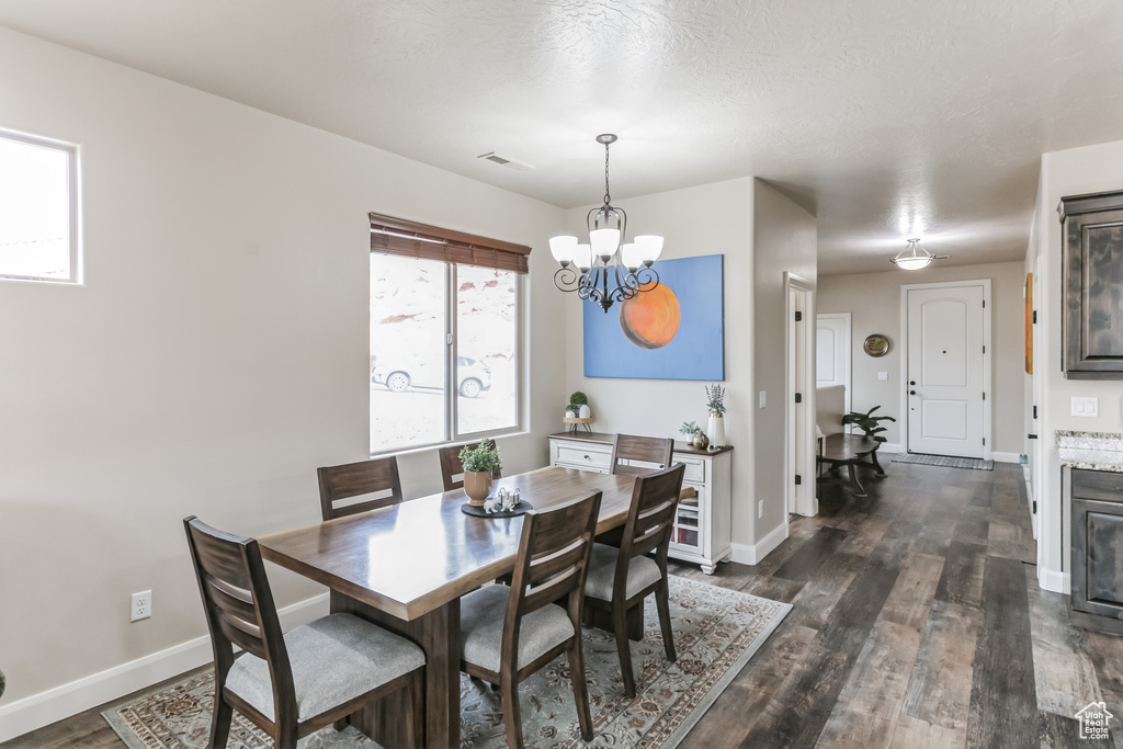 Dining room with a chandelier, dark wood finished floors, and baseboards