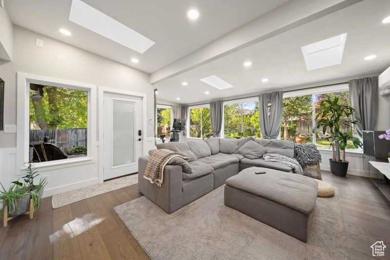 Living room featuring a skylight, wood-type flooring, vaulted ceiling, and recessed lighting