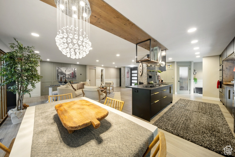 Dining area with a decorative wall, recessed lighting, a chandelier, and light wood finished floors