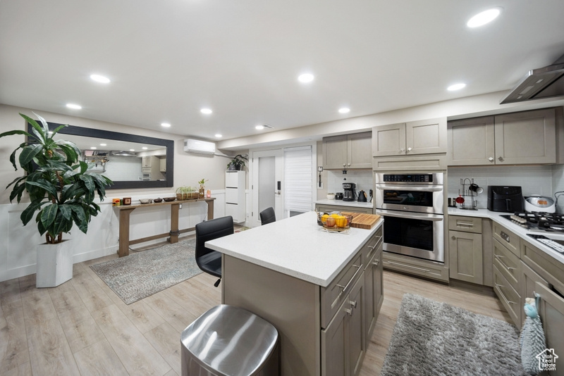 Kitchen featuring gray cabinetry, appliances with stainless steel finishes, a wall mounted air conditioner, light countertops, and light wood-style flooring