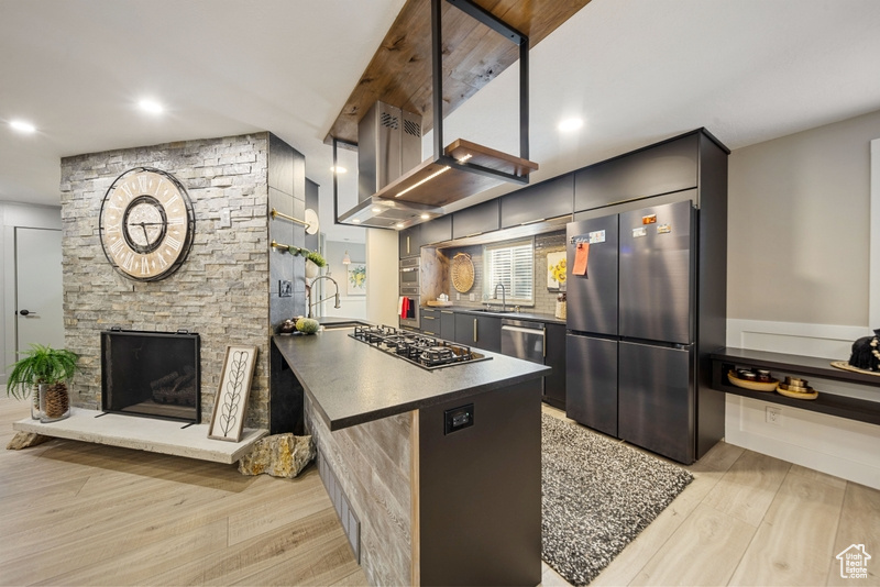 Kitchen featuring stainless steel appliances, a sink, light wood-style flooring, dark countertops, and recessed lighting