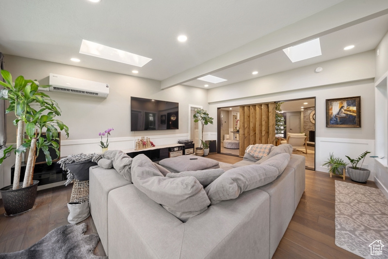 Living area featuring a skylight, a wall mounted air conditioner, wood finished floors, and recessed lighting