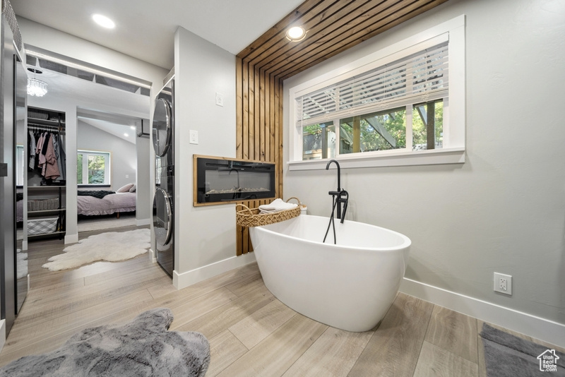 Bathroom featuring baseboards, a soaking tub, wood finished floors, and recessed lighting