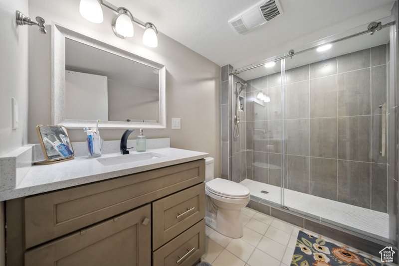 Bathroom with toilet, vanity, a shower stall, and tile patterned floors
