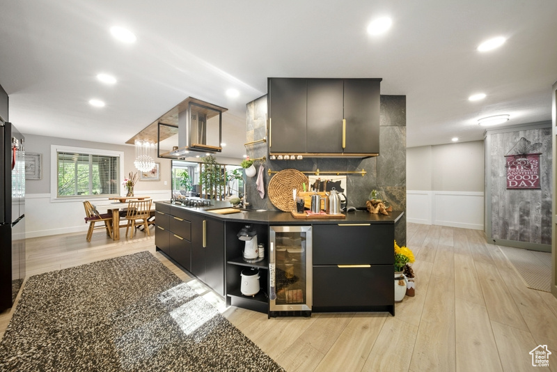 Bar with wine cooler, light wood-style flooring, island range hood, recessed lighting, and wainscoting