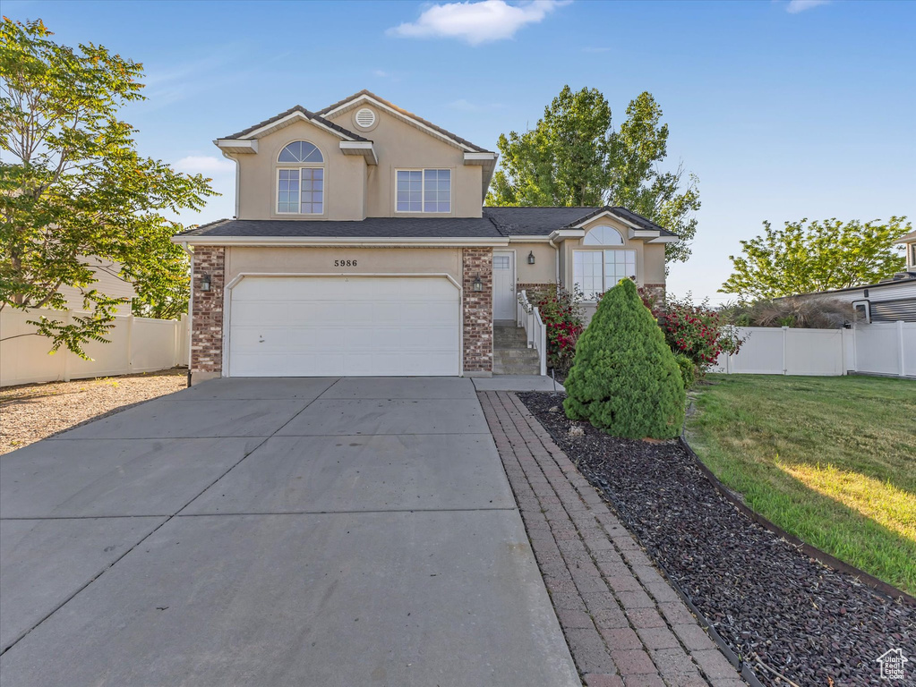 Traditional-style home with a garage, concrete driveway, stucco siding, and brick siding