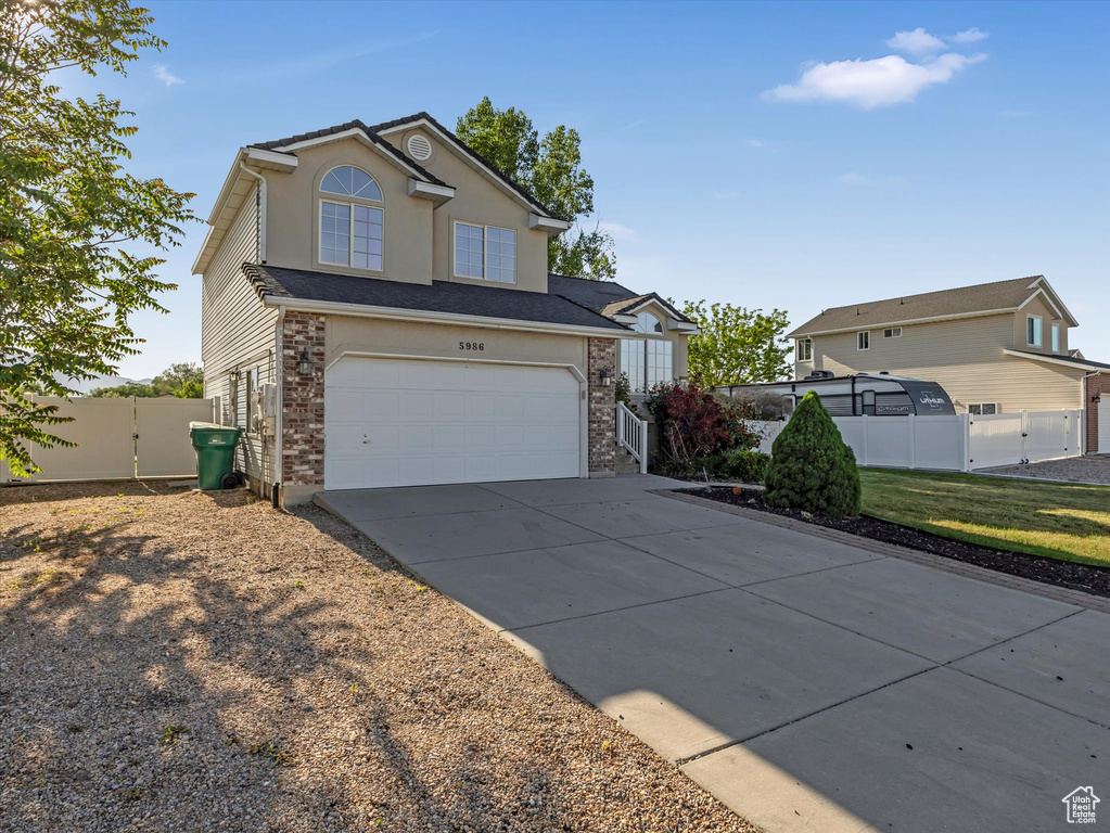 Traditional-style house with a gate, concrete driveway, and an attached garage