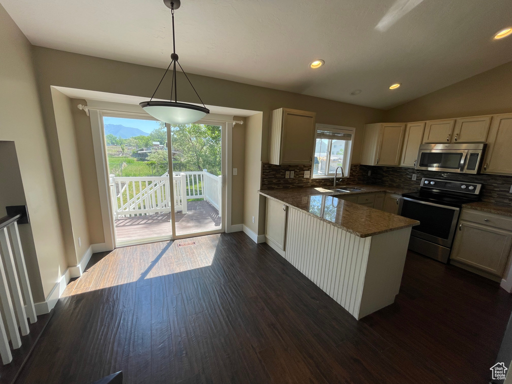 Kitchen with appliances with stainless steel finishes, a sink, a peninsula, decorative backsplash, and lofted ceiling