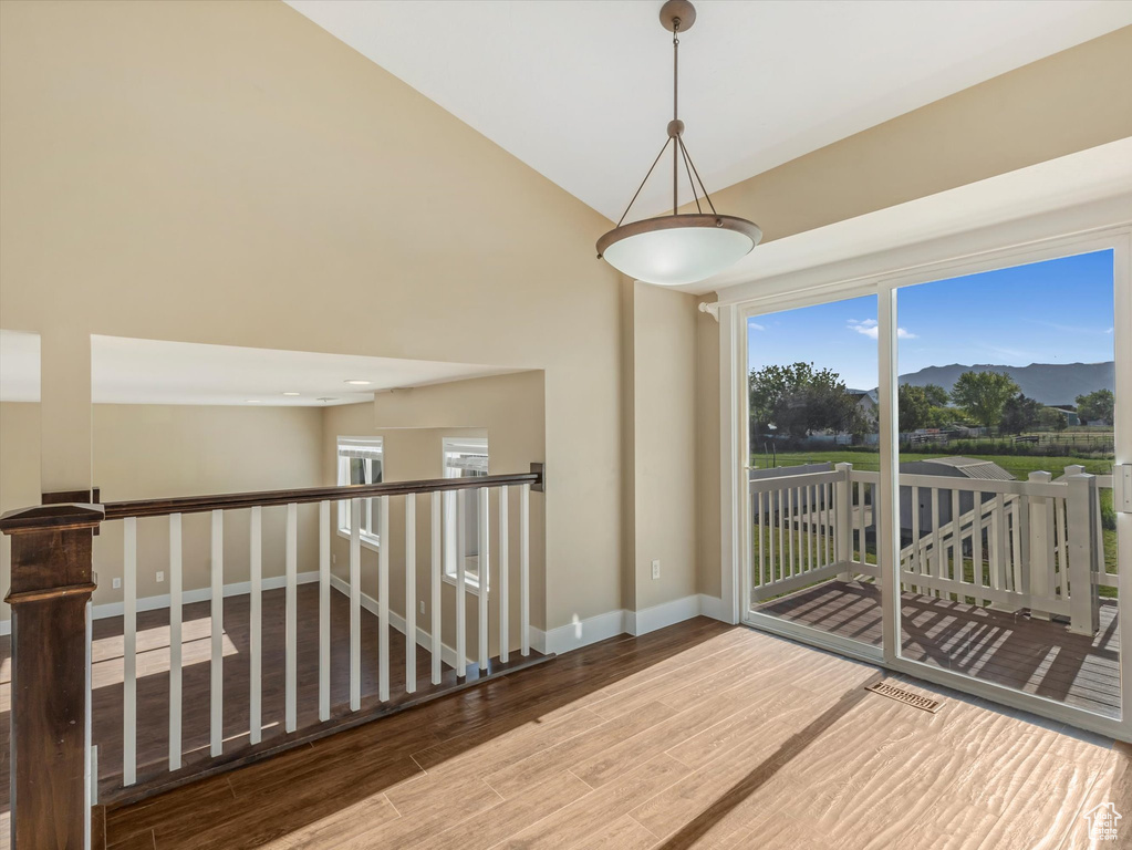 Spare room featuring wood finished floors, baseboards, a mountain view, and high vaulted ceiling