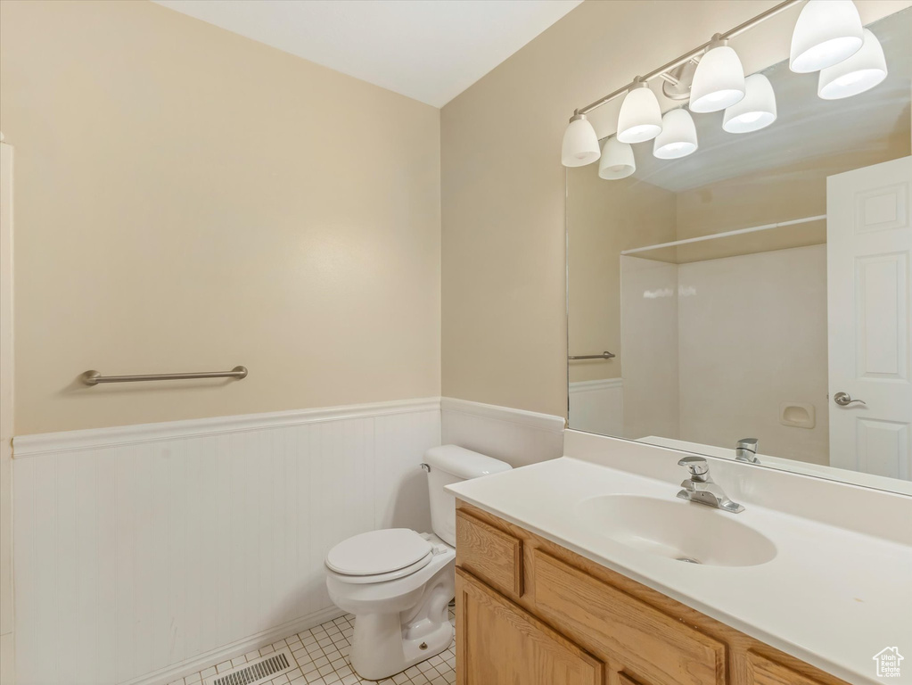 Full bathroom featuring wainscoting, toilet, vanity, tile patterned floors, and a shower