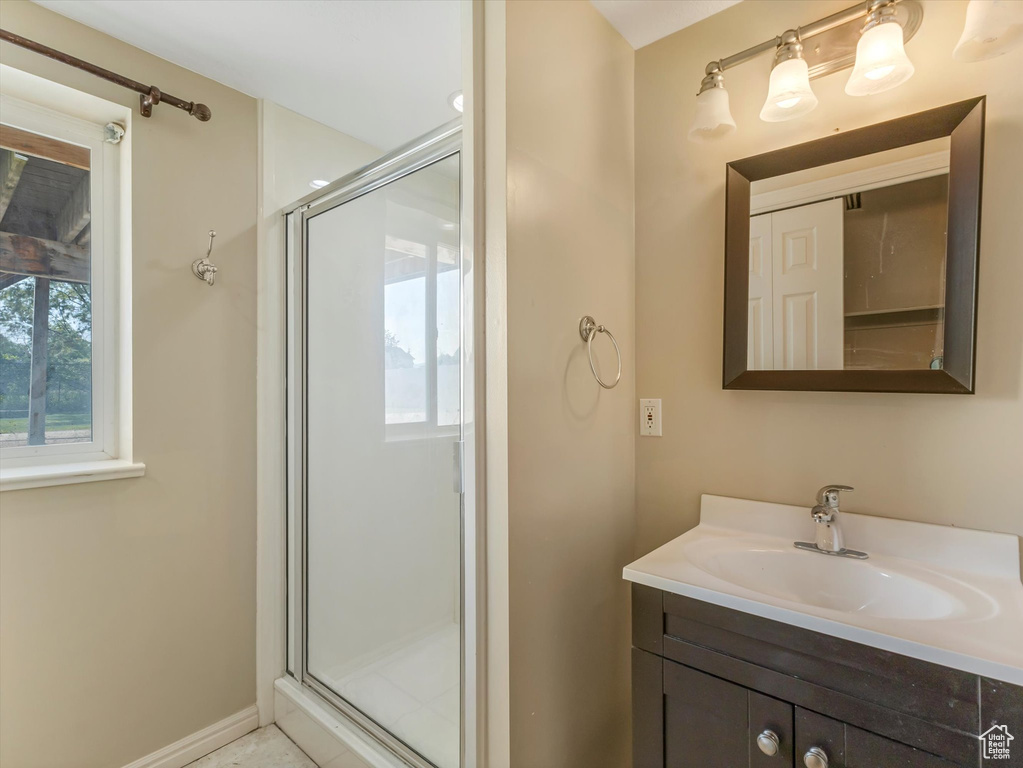 Full bathroom with vanity, a shower stall, and baseboards